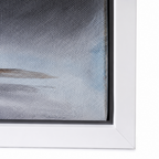 Close-up of a framed wall art piece showing part of a textured abstract landscape in soft blue, gray, and white tones with a white frame.
